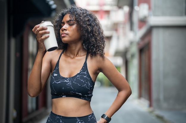 African woman sport healthy fit and firm slim drink water from cup on the hand athletic running wearing in the sportswear at city and town Fitness and sport motivation Runner concept