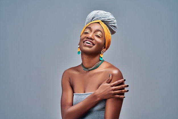 African  woman standing over isolated grey wall hugging oneself happy and positive smiling confident