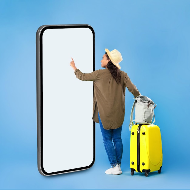 African woman traveler using huge smartphone on blue background square