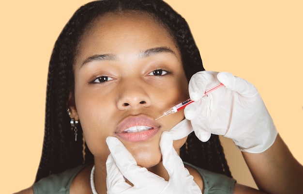 Photo african woman undergoing beauty botox treatmentplastic surgery. young african woman receiving botox injection in criss-cross zone at beauty clinic