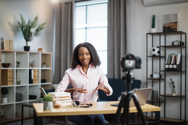 African woman using camera for live stream at home