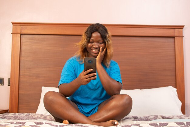 African woman using her phone in bed