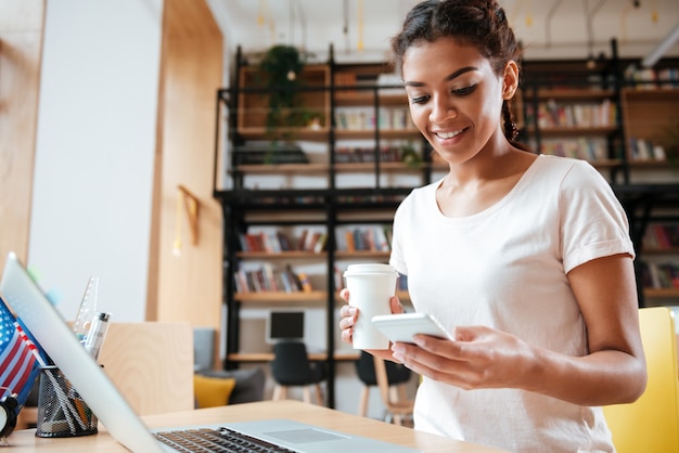 Donna africana che utilizza telefono nella biblioteca