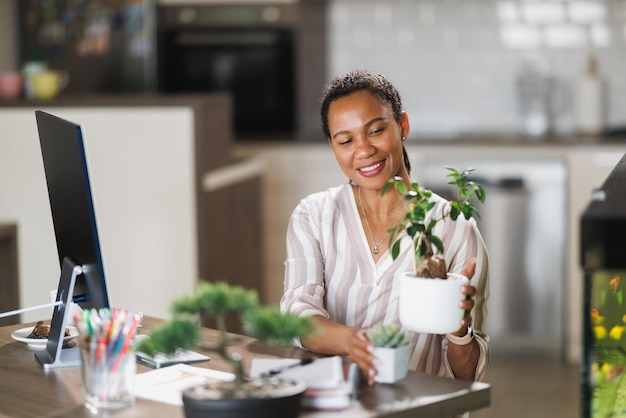 Photo african woman vlogging about plant care while working on a computer from her home office.