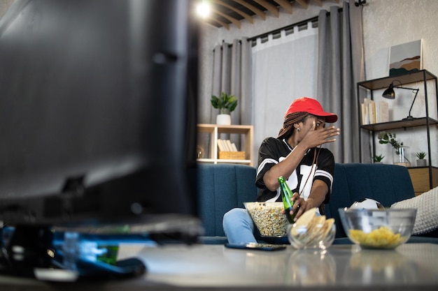 African woman watching soccer game alone at home