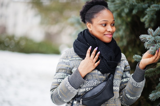 African woman wear in black scarf stand neae new year tree in winter day