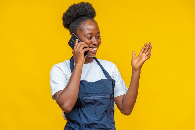 African woman wearing an apron making a phone call