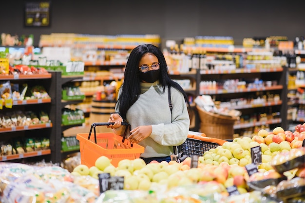 African woman wearing disposable medical mask. shopping in\
supermarket during coronavirus pandemia outbreak. epidemic\
time.