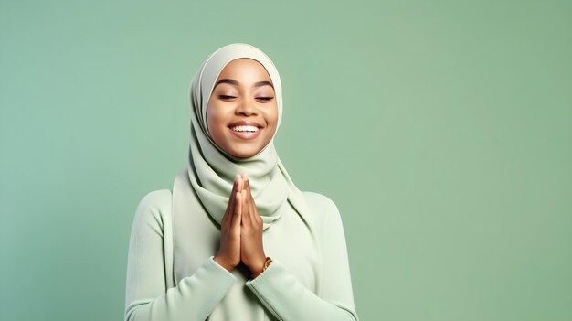 African woman wearing scarf is praying and smiling on green background