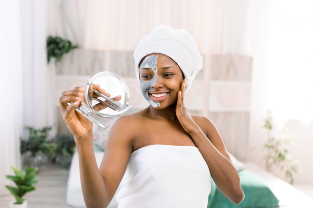 African woman wearing a towel and facial mask on half of face