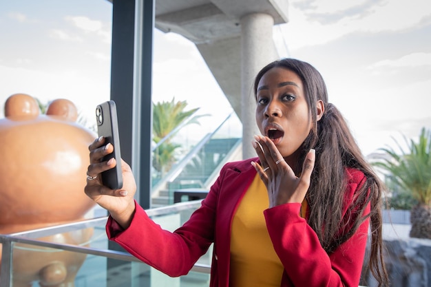 African woman with surprised face using her smart phone businesswoman at work