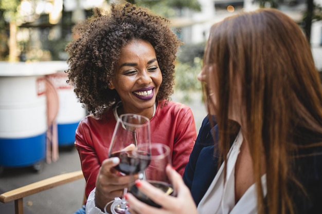 照片非洲的女人和她的女朋友露齿微笑举杯庆祝两个女人爱玩得开心在餐馆喝红酒