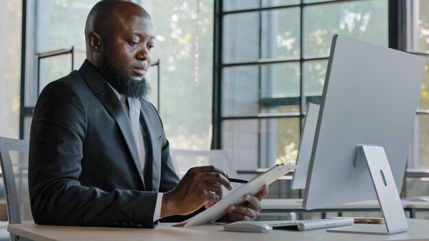 African writer writing notes on paper tablet sit at office desk adult entrepreneur american