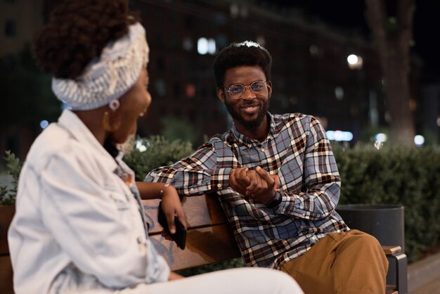 african young couple sitting on the bench and talking during their date in the park