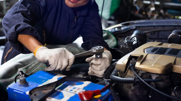 アフリカの若い女性の自動車整備士のチェックとサービス車のガレージで車のエンジンの修理