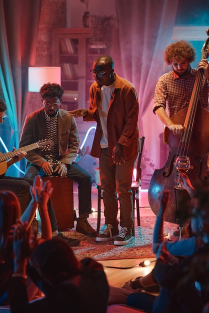 Photo african young man singing while his band playing on instruments during performance in the club