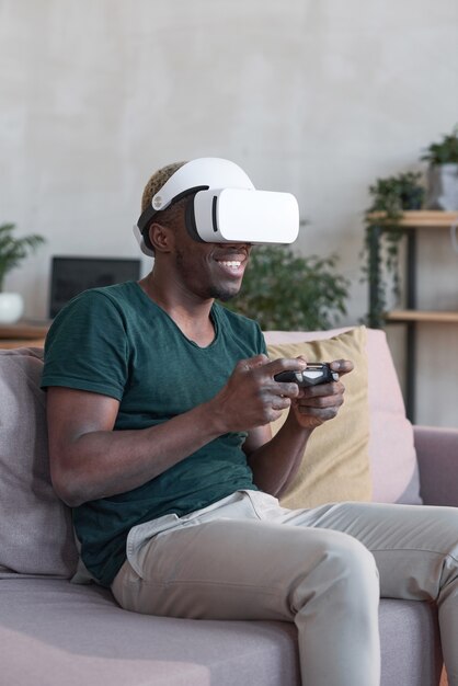 African young man with virtual reality headset and joysticks playing video games home