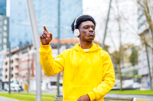 Photo african young man in yellow clothes dancing listening to music