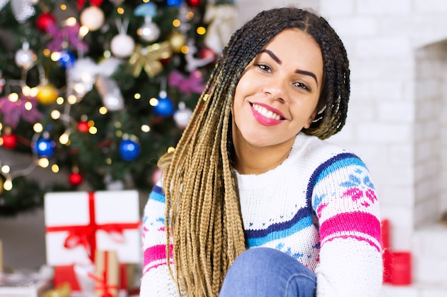 African young woman on Christmas Eve decorated living room