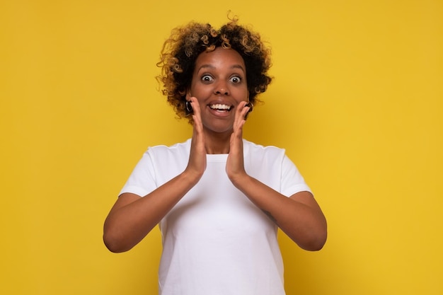 African young woman clasping hands in applause saying wow