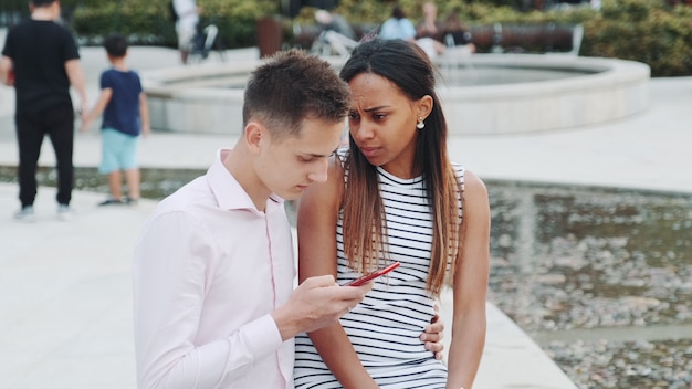 African young woman is upset because of her boyfriend looking in the smartphone all the time