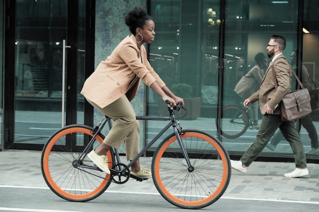 Фото Африканская молодая женщина, едущая на велосипеде на работу по улицам города