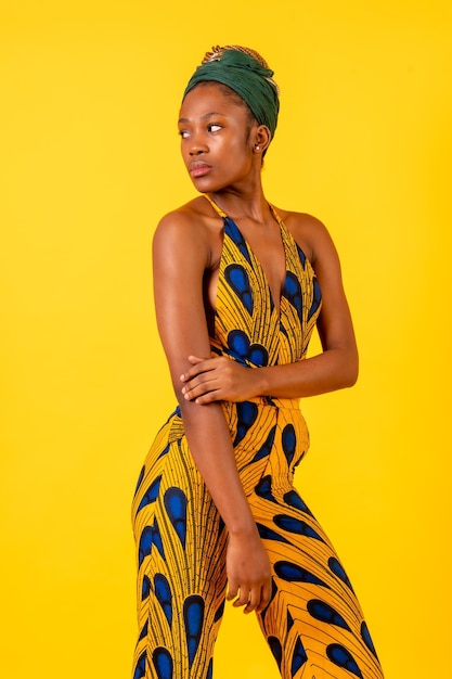 African young woman in the studio on a yellow background portrait in a traditional costume looking