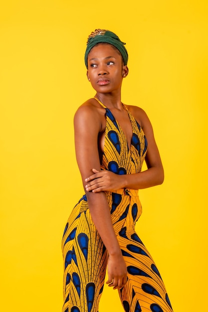 전통 의상을 입은 노란색 배경 초상화에 스튜디오에 있는 아프리카 젊은 여성