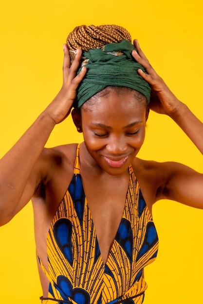 African young woman in traditional dress on yellow background with green turban