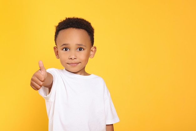 africanamerican boy showing thumb up on yellow background space for text