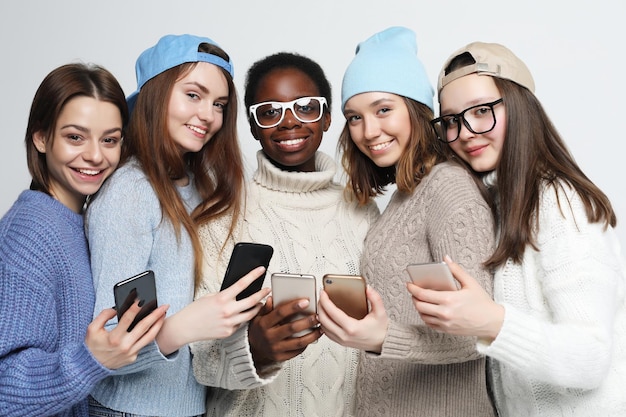 アフリカ系アメリカ人と白人の女性がスマートフォンを見て、ソーシャルネットワークでオンラインでチャットしている