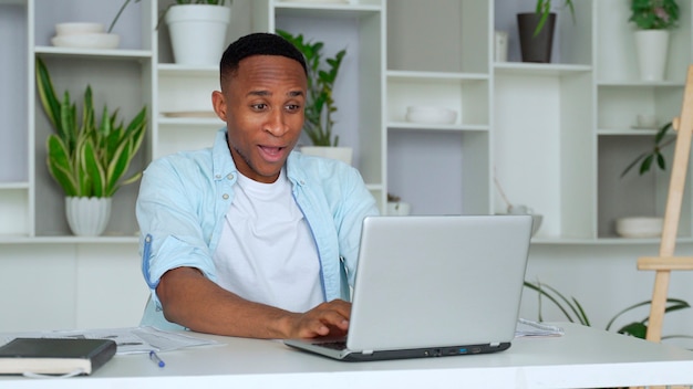 L'afroamericano si sente felice di aver ricevuto ottime notizie da internet guarda lo schermo del pc le mani alzate urlano di gioia mentre celebra la vincita alla lotteria online