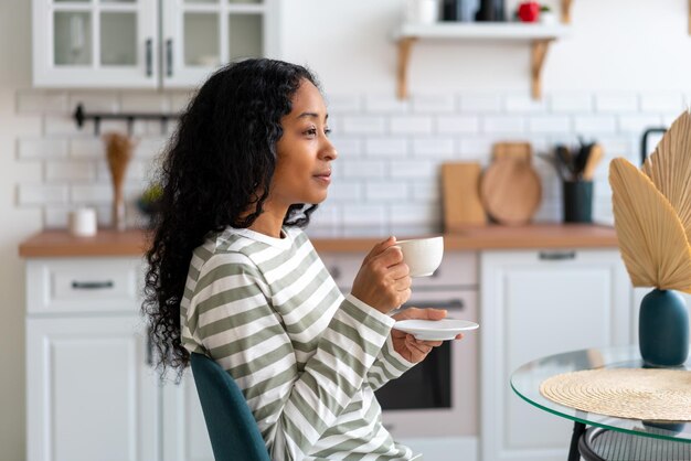 スローリビングライフスタイルの朝のコンセプトでお茶を飲むアフリカ系アメリカ人の女性