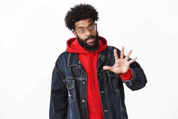 Africanamerican guy asking five minutes as meeting friend showing fifth with palm and looking at camera promising not taking much time as explaining himself to exgirlfriend over gray background