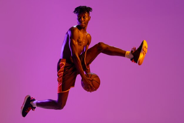 Africanamerican male basketball player in motion and action isolated on purple