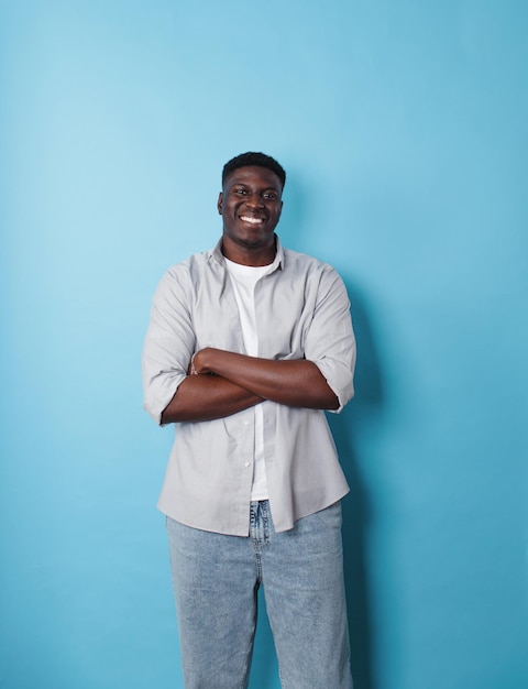 An AfricanAmerican man in white clothes stands on an isolated blue background