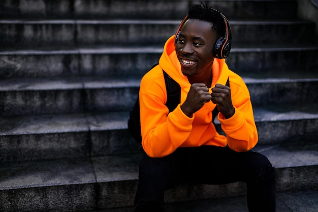 Афроамериканец в беспроводных наушниках слушает музыку