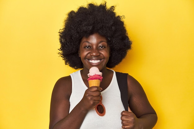 AfricanAmerican woman enjoying ice cream on a yellow studio background