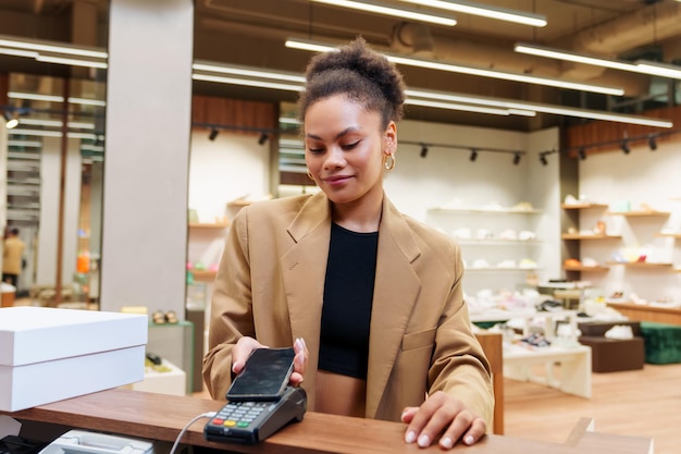 Foto una donna afroamericana paga un acquisto utilizzando uno smartphone in un negozio