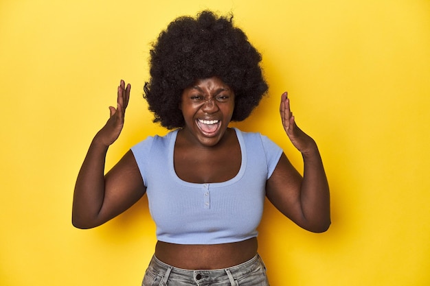 Photo africanamerican woman with afro studio yellow background screaming to the sky looking up frustrated