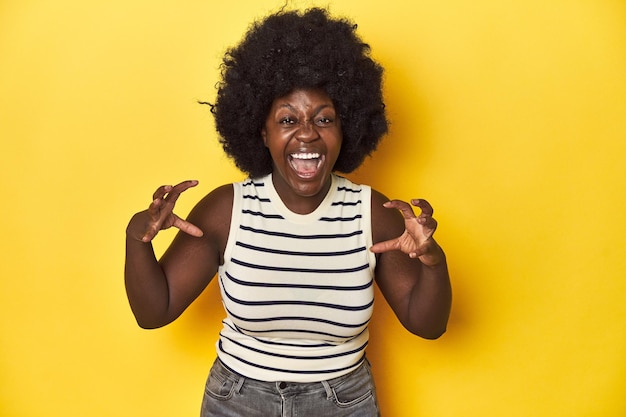 Photo africanamerican woman with afro studio yellow background screaming with rage