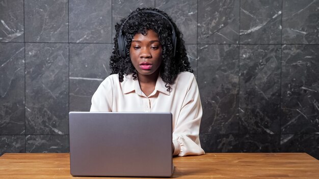 Africanamerican woman with headphones at video chat by wall