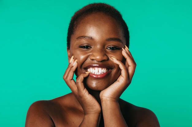 Africanamerican young model with dark perfect skin looking at camera and touching her cheeks posing