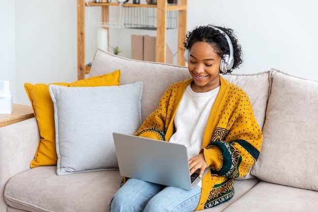 Afrikaans amerikaans meisje met behulp van laptop thuis kantoor kijken naar scherm typen chatten lezen schrijven