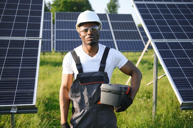 Afrikaans-Amerikaanse ingenieur die zonnepanelen onderhoudt Technicus die buiten werkt aan de bouw van ecologische zonneparken Concept voor hernieuwbare schone energie technologie