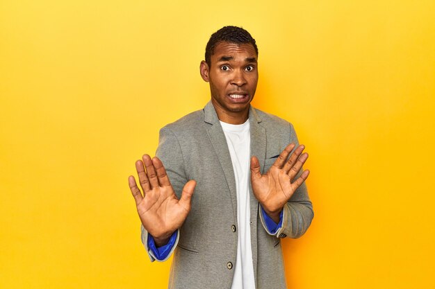 Afrikaans-Amerikaanse man in een casual blazer gele studio die iemand afwijst met een gebaar van walging