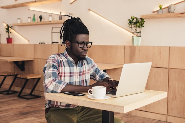 Afrikaans-Amerikaanse man met laptop en smartphone in een koffieshop