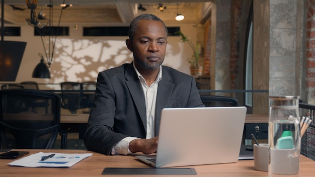 Afrikaans-Amerikaanse ondernemer van middelbare leeftijd die een laptop schrijft etnische zakenman kantoor