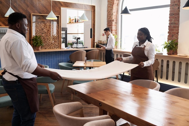 Afrikaans-Amerikaanse serveerders zetten tafel op het werk in een restaurant