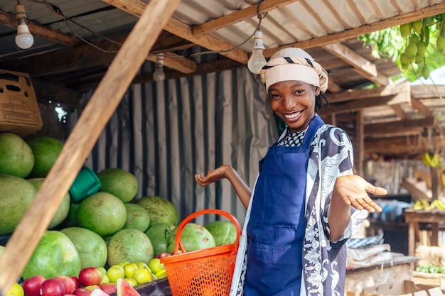 Foto afrikaans-amerikaanse winkelbediende verwelkomt klanten bij een fruitstand